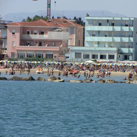 Crowded beach with colorful umbrellas and buildings in the background.