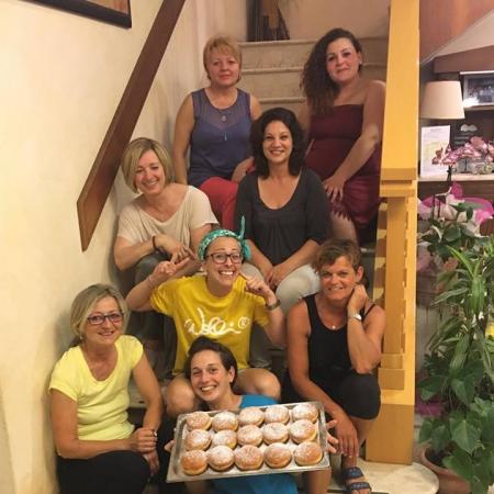 Group of smiling women with a tray of pastries on stairs.