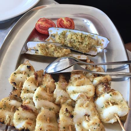 Squid skewers and gratinated mussels on a steel plate.