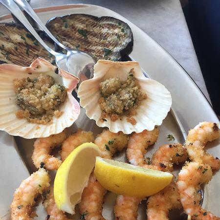 Shrimp skewers and gratinated scallops with lemon.