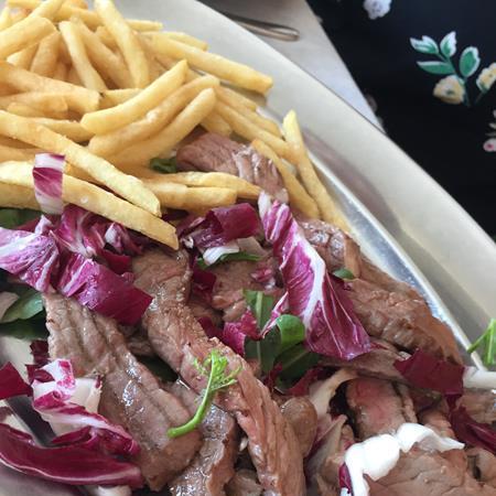 Meat with radicchio and fries on a plate.