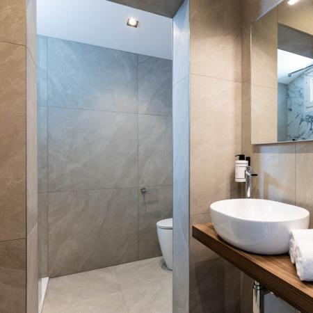 Modern bathroom, elegant, with white sink and soft towels on wooden shelf.