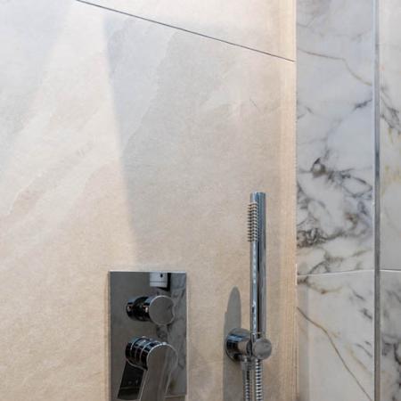 Modern shower with elegant marble and shiny steel, evoking luxury and serenity.
