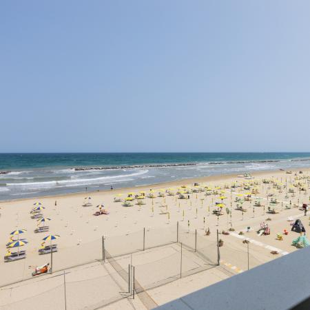 Sunny beach with colorful umbrellas, calm sea, and clear sky.