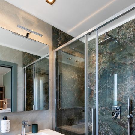 Elegant modern bathroom with marble shower and minimalist sink.