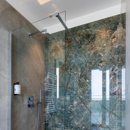 Elegant shower with green marble walls and modern tiles.