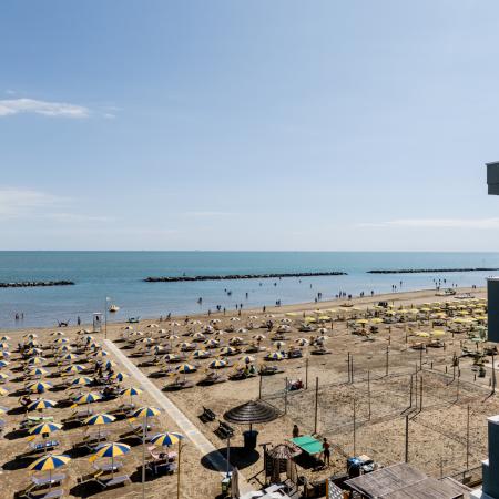 Sunny beach with colorful umbrellas, calm sea, and summer vibes.