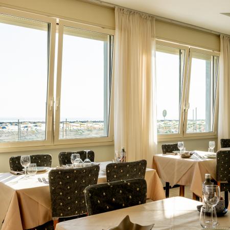 Bright restaurant with sea view and elegant tables, relaxing atmosphere.