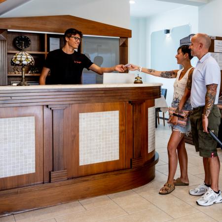Happy couple receives hotel keys, exciting vacation begins.