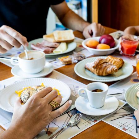 Joyful family breakfast with pastries, fruit, and coffee.