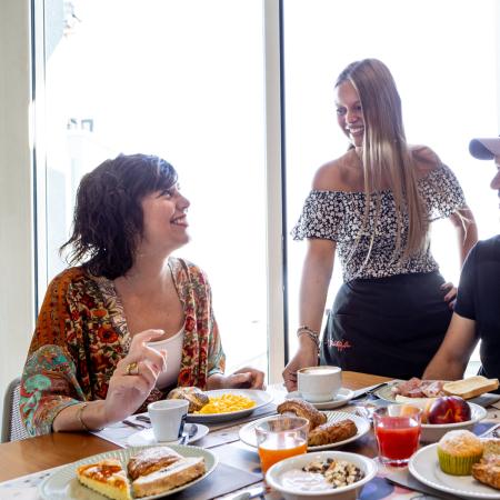 Joyful breakfast with friends, smiles, and treats on a sunny table.