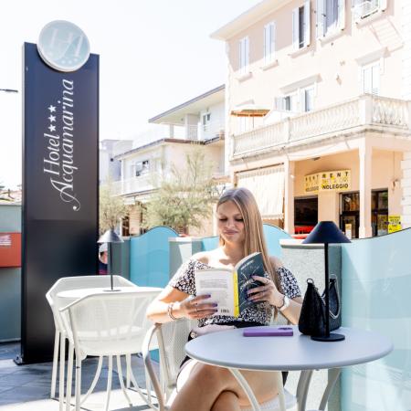 Woman reading relaxed on hotel terrace, sun and peaceful atmosphere.