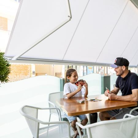 Playing cards with smiles under an awning, a relaxed and friendly atmosphere.