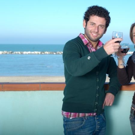 Two people toast with the sea in the background.