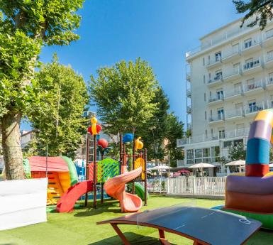 Parco giochi colorato davanti a un edificio bianco con balconi.