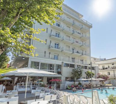 Hotel con piscina all'aperto, sedie a sdraio e ombrelloni.