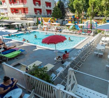 Piscina all'aperto con lettini e area giochi.