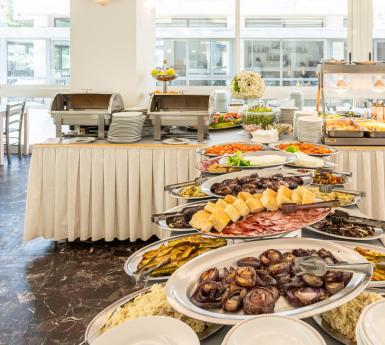 Buffet con piatti vari, verdure e formaggi in un ambiente luminoso.