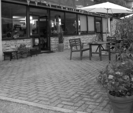 Outdoor terrace with tables and chairs, near a restaurant.