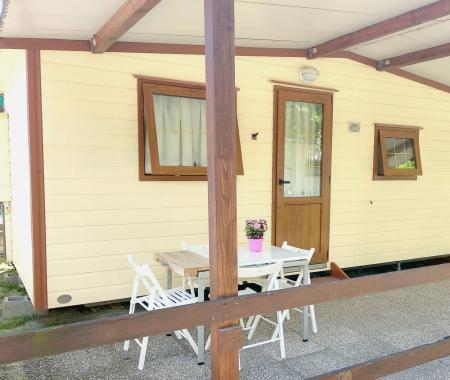 Small house with porch, white table and chairs, flowers on the table.