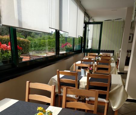 Salle à manger lumineuse avec des tables dressées et des fleurs.