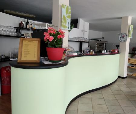 A bar with a curved counter, wall clock, and displayed menu.