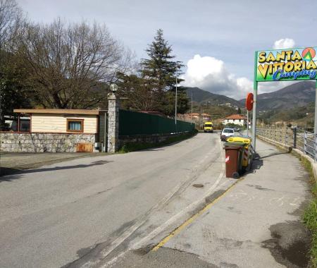 Eingang des Campingplatzes Santa Vittoria mit Mülltonnen und Straße.