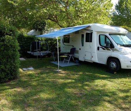 White camper parked with awning extended in a green area.