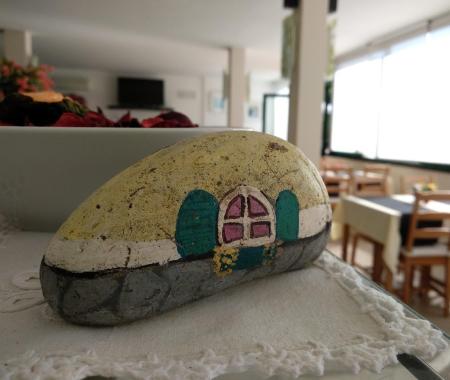 Painted stone with a house, in a bright room with tables and chairs.