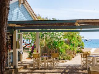Terrasse am Meer mit Tischen und Yacht in der Ferne.