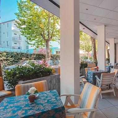 Terrazza all'aperto con tavoli e sedie, ambiente accogliente.