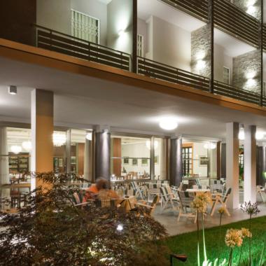 Hotel moderno con terrazza e giardino illuminato di notte.