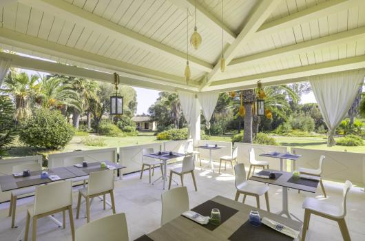 Elegante veranda con tavoli e vista sul giardino tropicale.