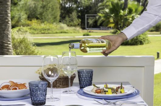 Pranzo all'aperto con vino bianco, piatti gourmet e bicchieri eleganti.