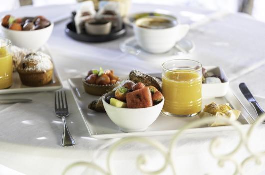 Colazione con frutta, succo d'arancia e dolci su tavola apparecchiata.