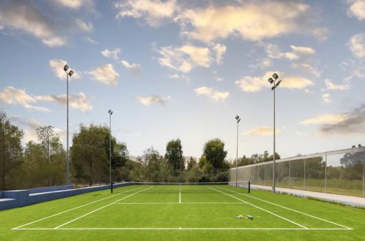 Campo da tennis su erba con racchette, cielo sereno.