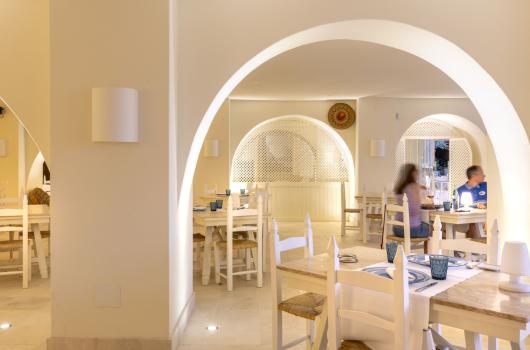 Ristorante elegante con archi bianchi e arredamento rustico.