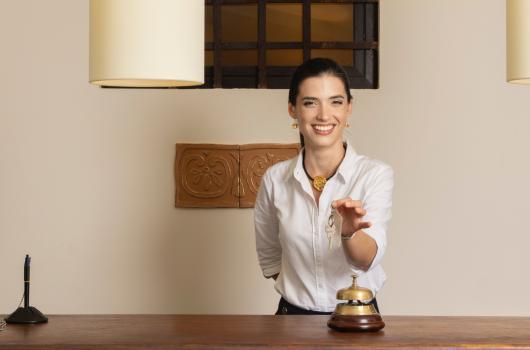 Receptionist sorridente con chiavi in mano al banco.