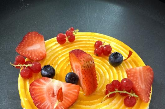 Dessert decorato con frutta fresca su base gialla.