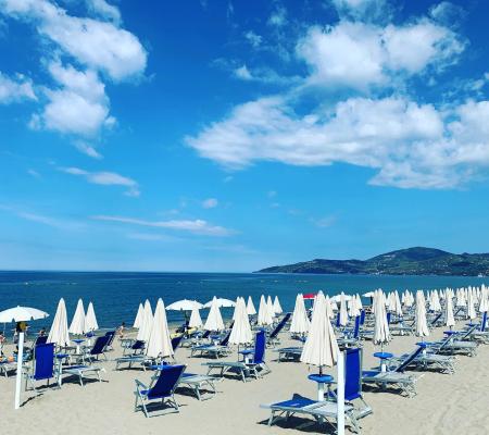 Strand mit Sonnenschirmen und Liegen unter blauem Himmel.