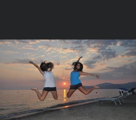 Zwei Personen springen am Strand bei Sonnenuntergang.