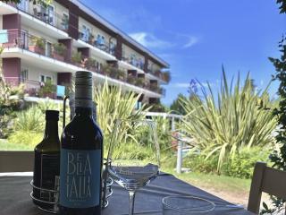 Wine bottle on outdoor table, view of building and garden.
