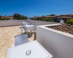 Terrazza con tavoli bianchi, vista sui tetti e cielo azzurro.