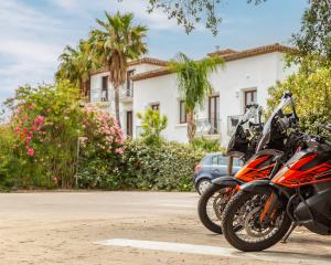 Due moto arancioni parcheggiate davanti a una villa con palme.