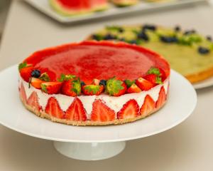 Torta alla fragola con decorazioni di frutta fresca su piatto bianco.