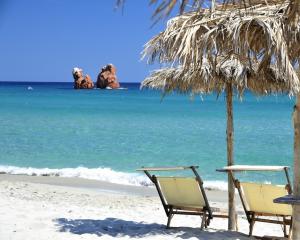 Spiaggia sabbiosa con ombrelloni e mare cristallino.