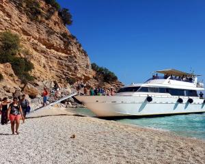 Barca attraccata su spiaggia con turisti che sbarcano.