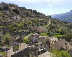 Rovine di un villaggio abbandonato tra le montagne verdi.