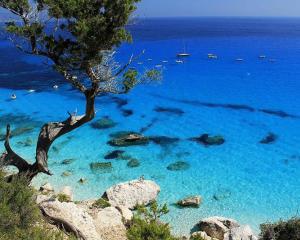 Spiaggia con acque cristalline e barche al largo.