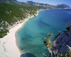 Spiaggia incontaminata con mare cristallino e montagne verdi.